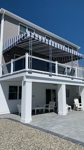 A large white house with a balcony and a striped awning - Freehold, NJ - Awning Design Inc