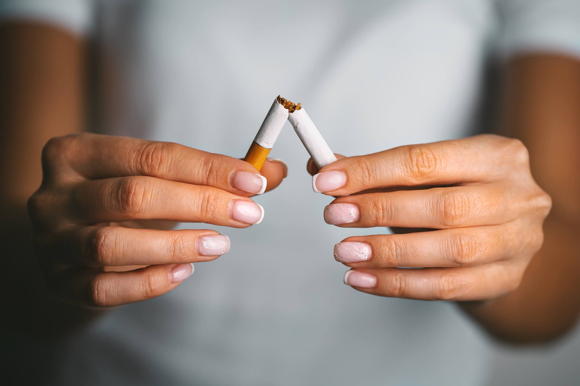 A woman is holding two broken cigarettes in her hands.