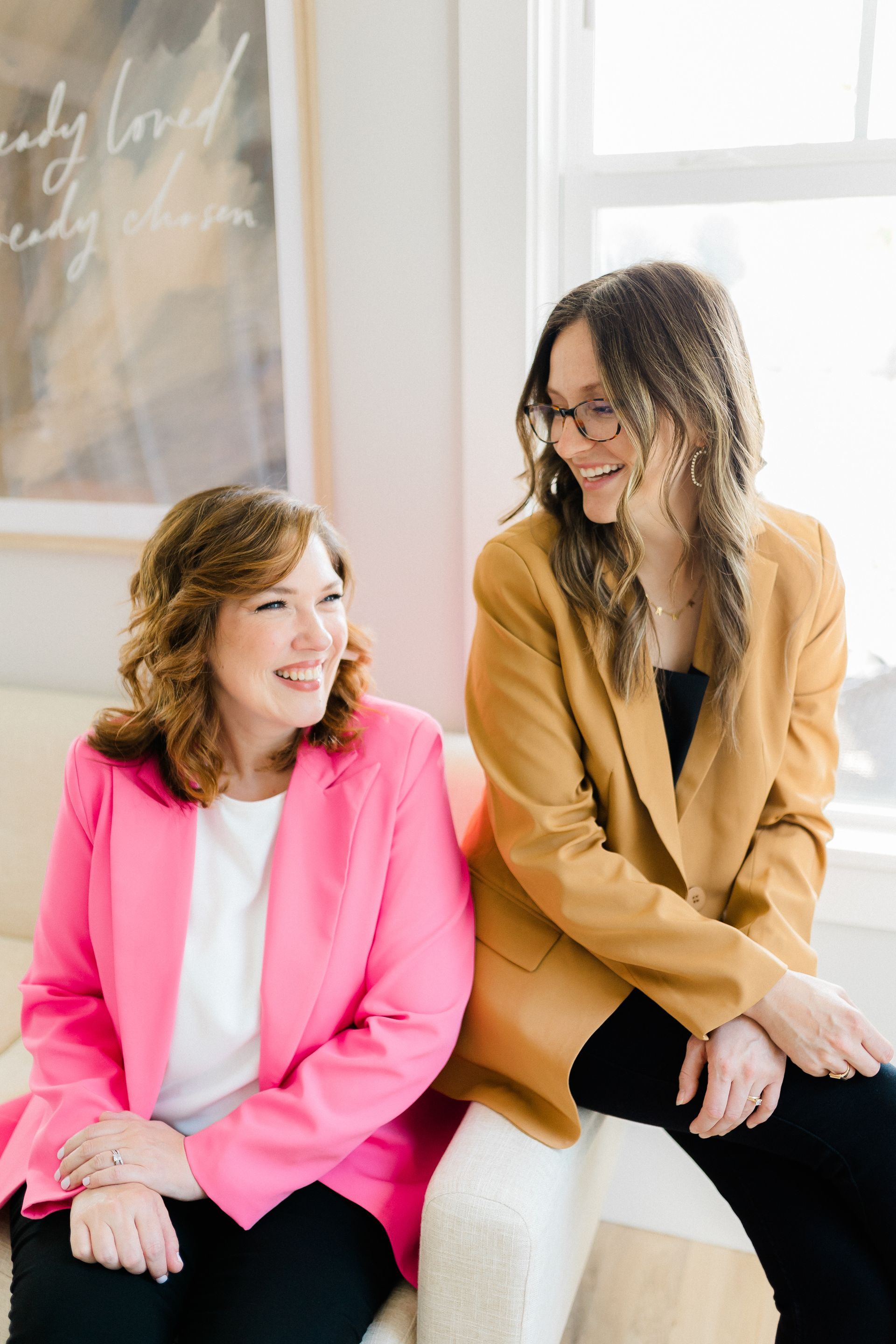 Two women are sitting next to each other on a couch.
