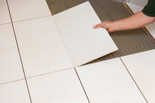 A tile fixer laying ceramic floor tiles into a bed of adhesive.