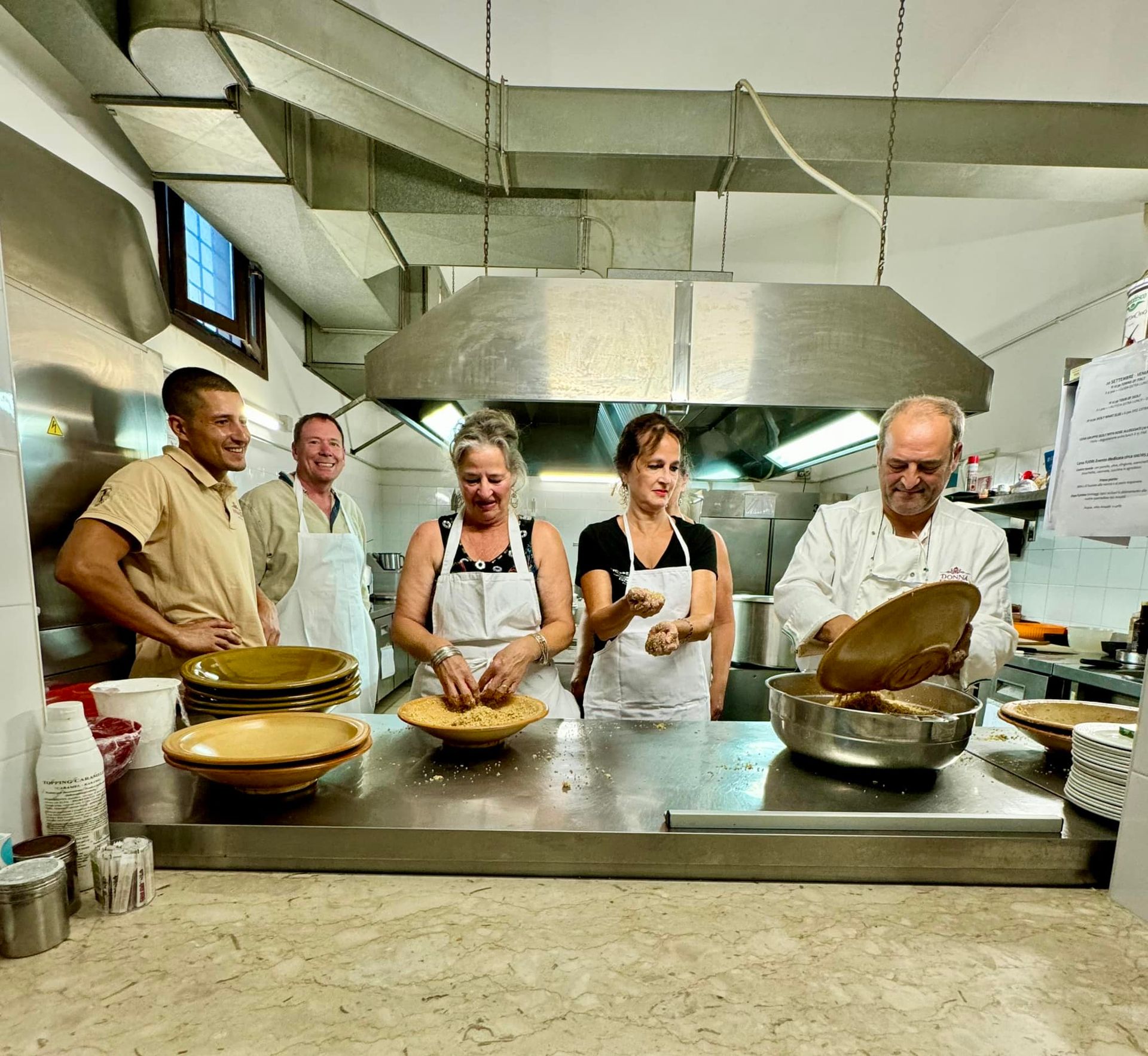 People preparing food in a commercial kitchen. Bowls on counter, chef tossing ingredients.