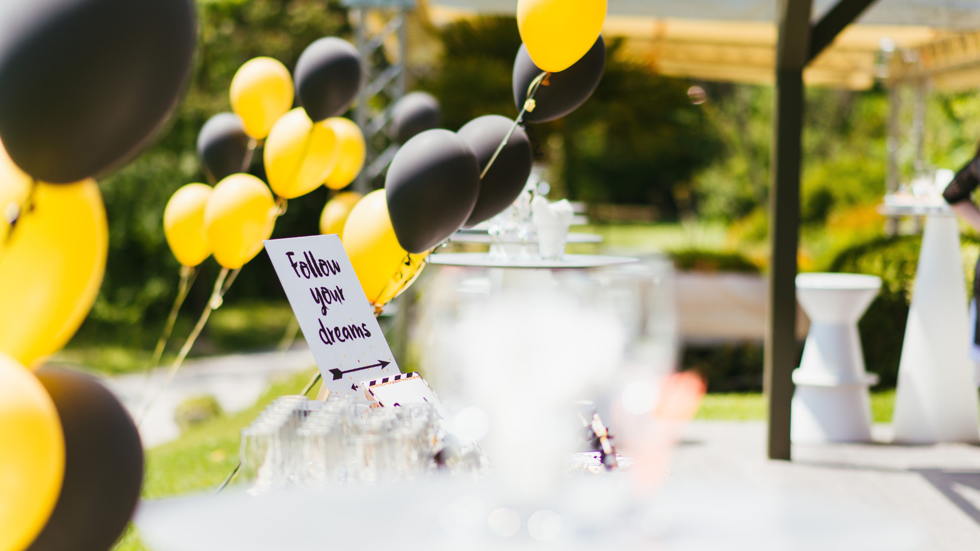 A bunch of yellow and black balloons are hanging from a string.