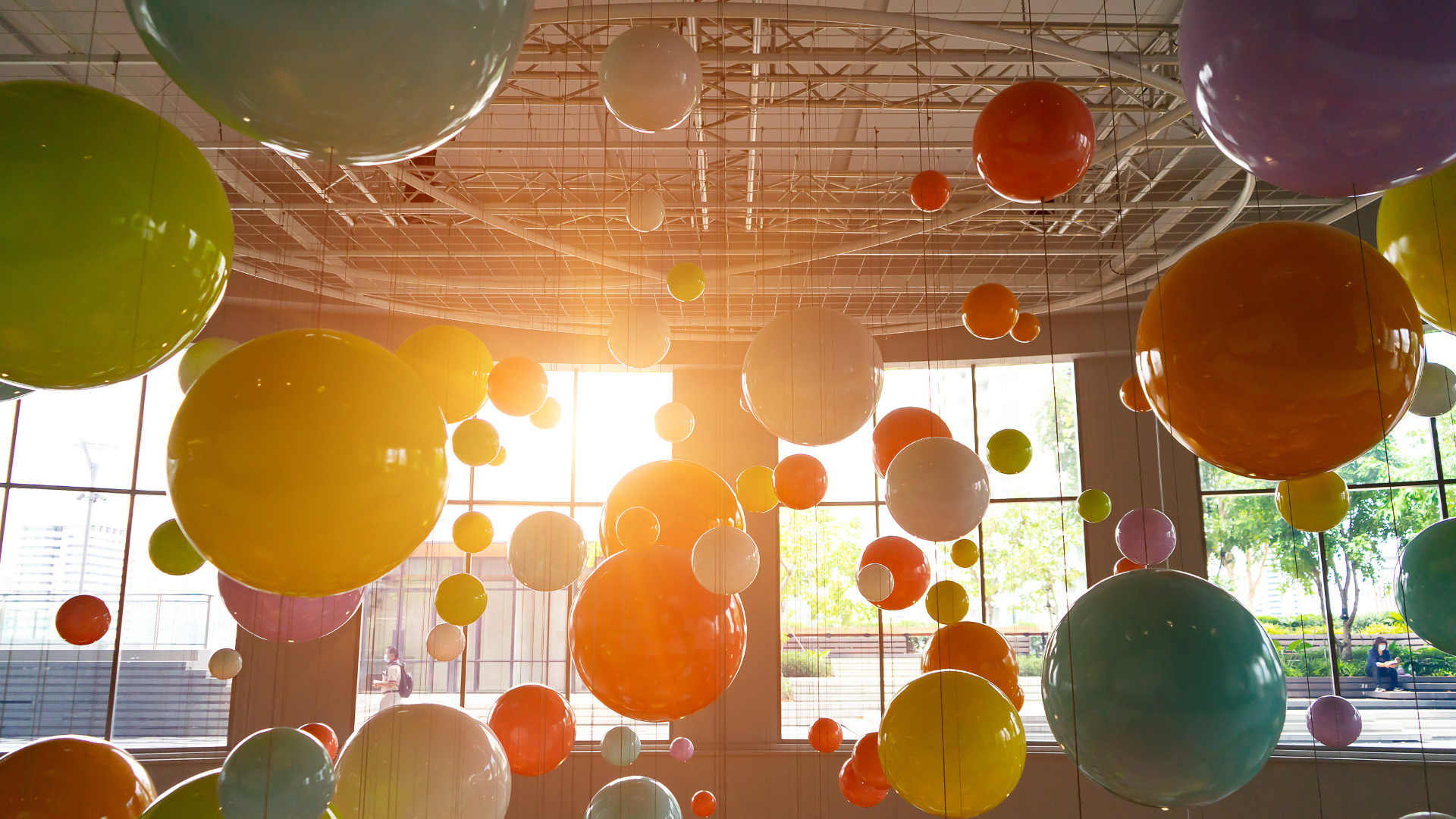 A bunch of colorful balloons are hanging from the ceiling