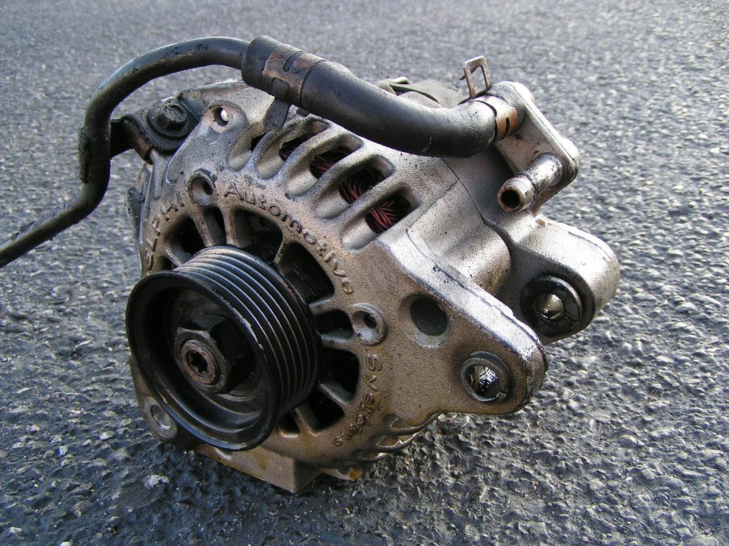 A close up of a car alternator on the ground