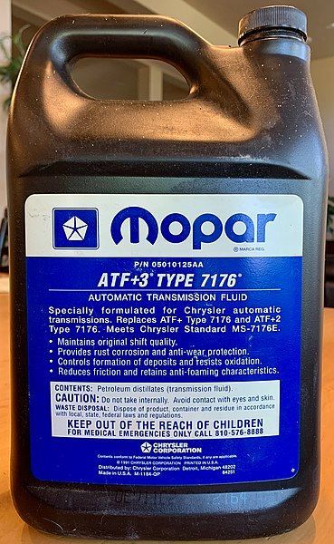 A gallon of mopar atf 3 type 7178 automatic transmission fluid is sitting on a wooden table.