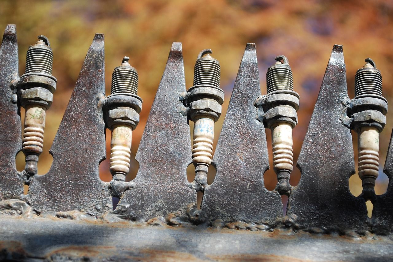 A row of spark plugs are lined up on a metal fence