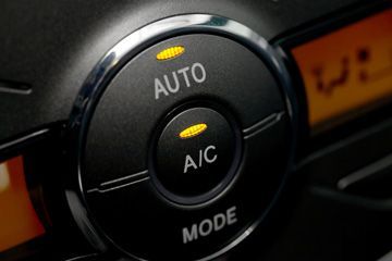 A close up of an auto and a/c mode button on a car dashboard.