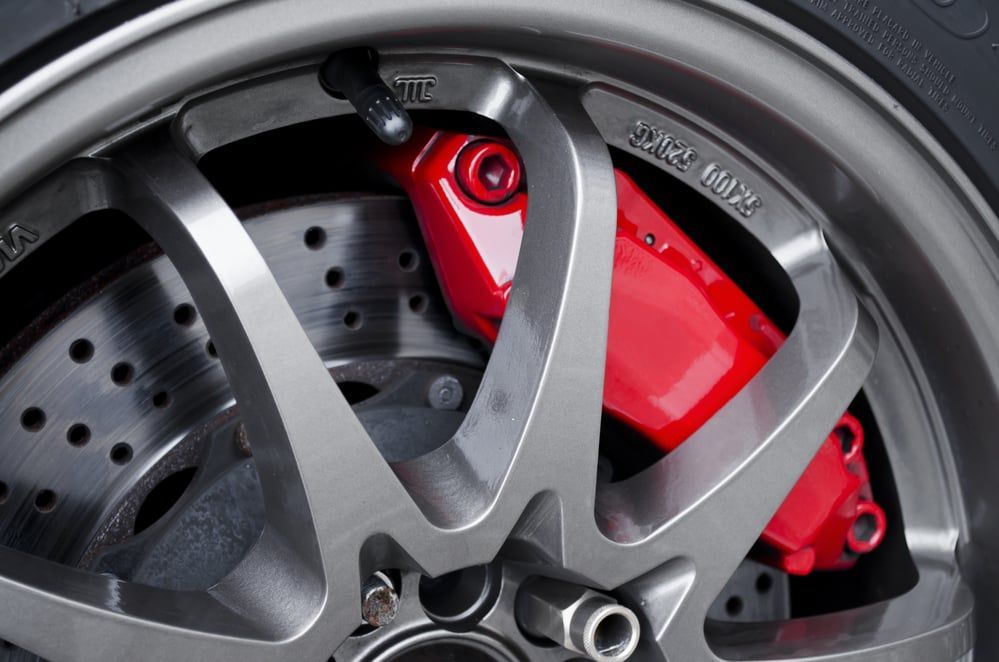 A close up of a car wheel with a red brake caliper