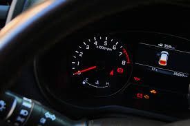 A close up of a car dashboard with a speedometer and a steering wheel.