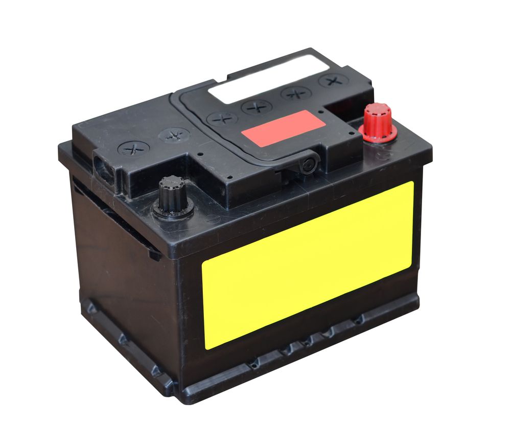 A black car battery with a yellow label on it