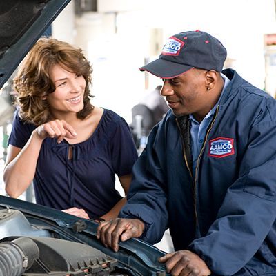 A man and a woman are looking under the hood of a car