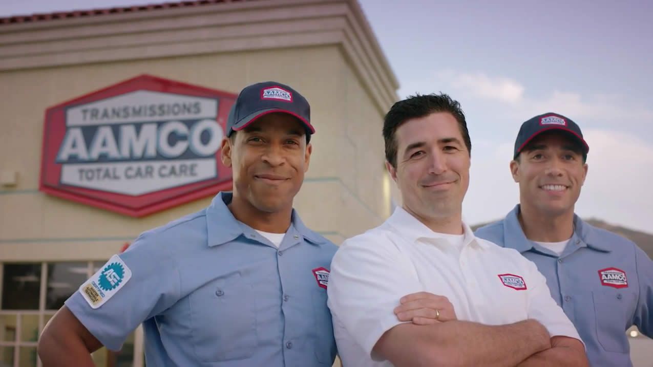 Three men standing in front of aamco total car care