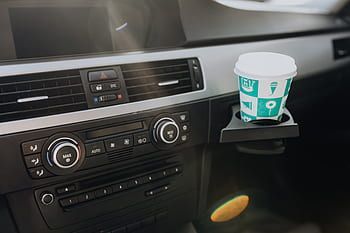 A cup of coffee is sitting in a cup holder on the dashboard of a car.