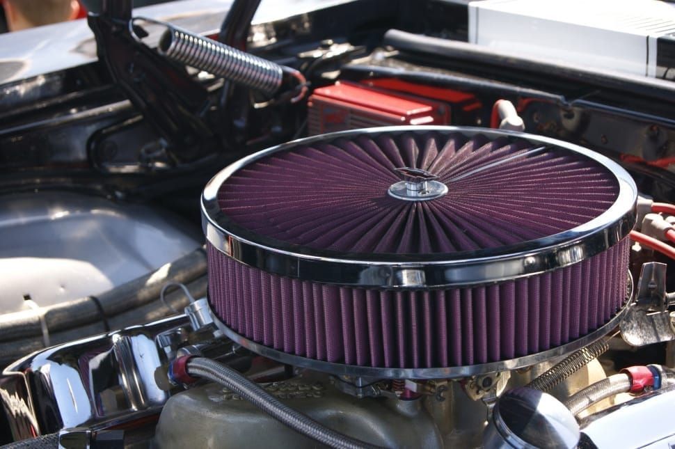 A close up of a car engine with a purple air filter