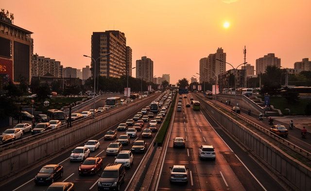 A busy highway with cars driving down it at sunset.