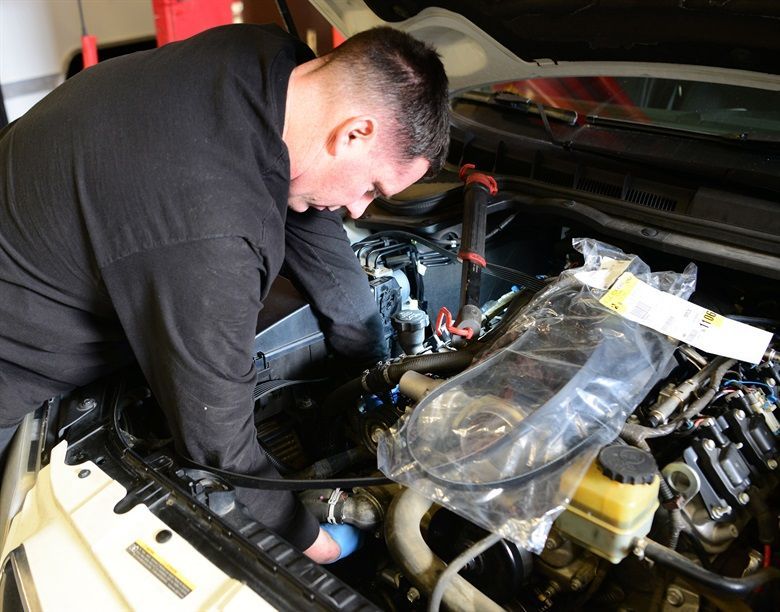 A man is working under the hood of a car