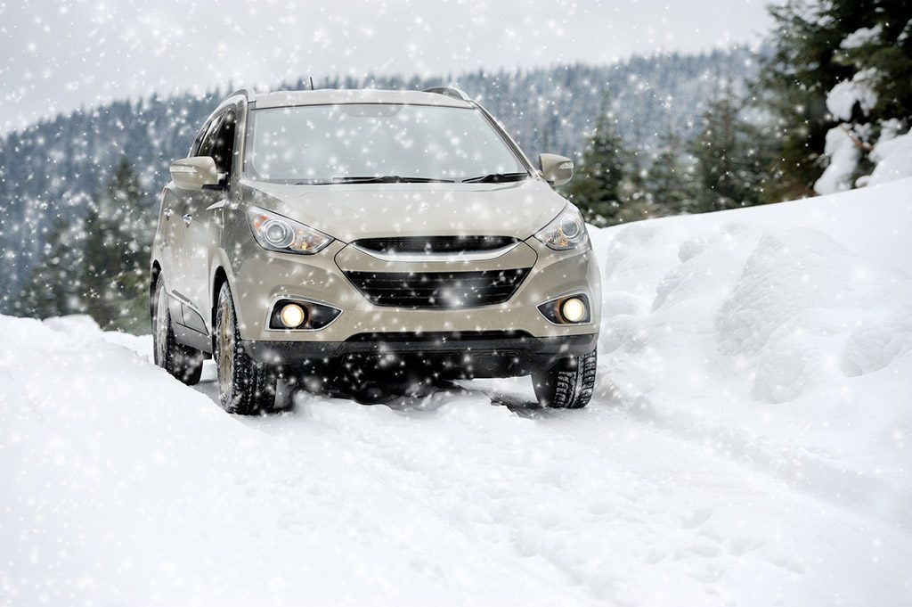 A car is driving through the snow on a snowy road.