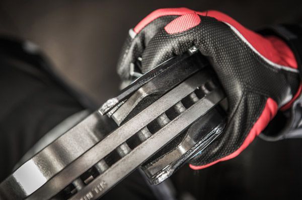 A person wearing red and black gloves is holding a brake disc.