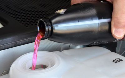 A person is pouring red liquid into a white tank.