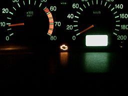 A close up of a car dashboard with a light on.