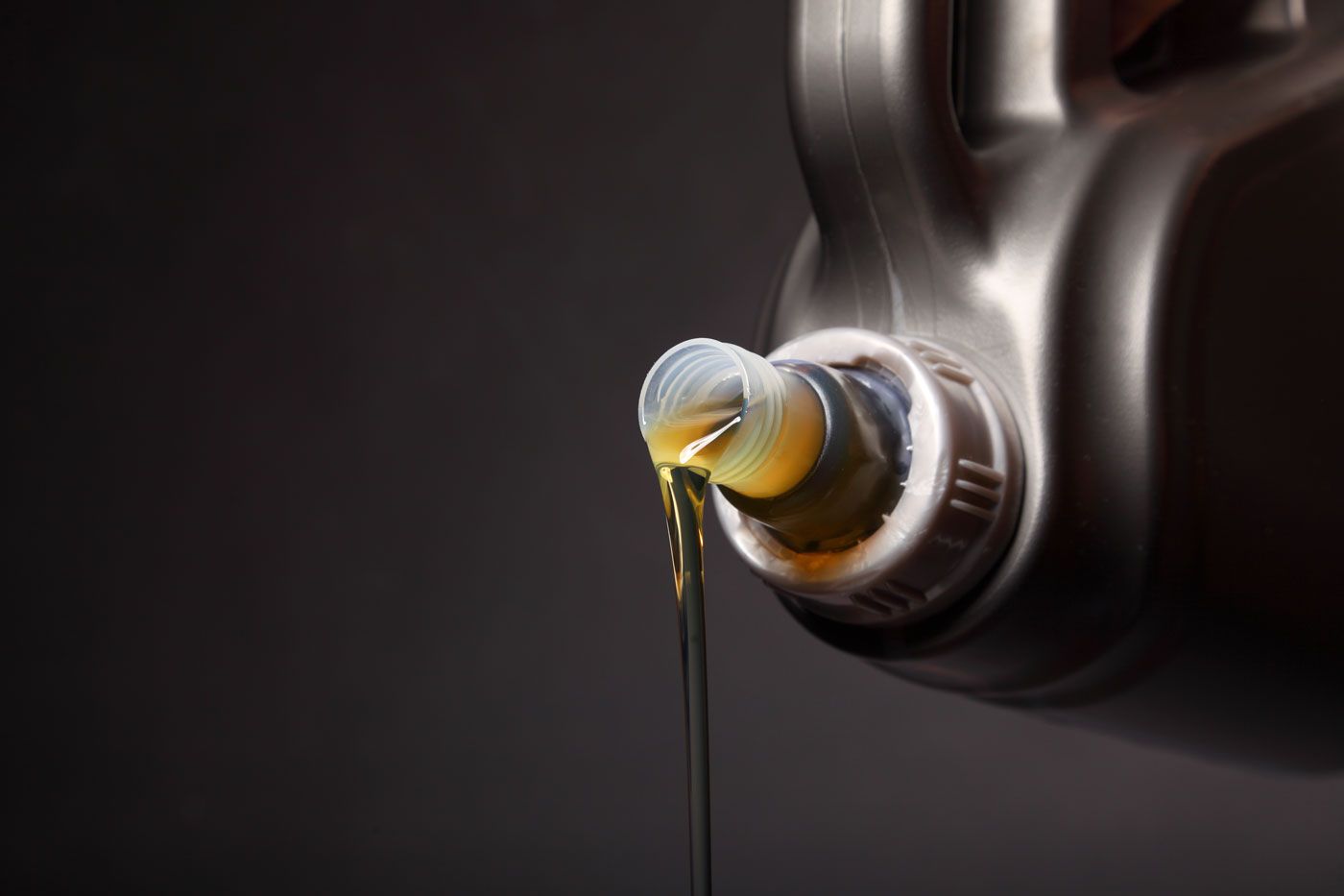 A close up of a bottle of oil being poured into a bottle.