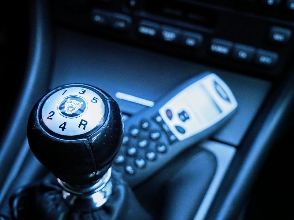 A remote control is sitting next to a gear shift in a car.