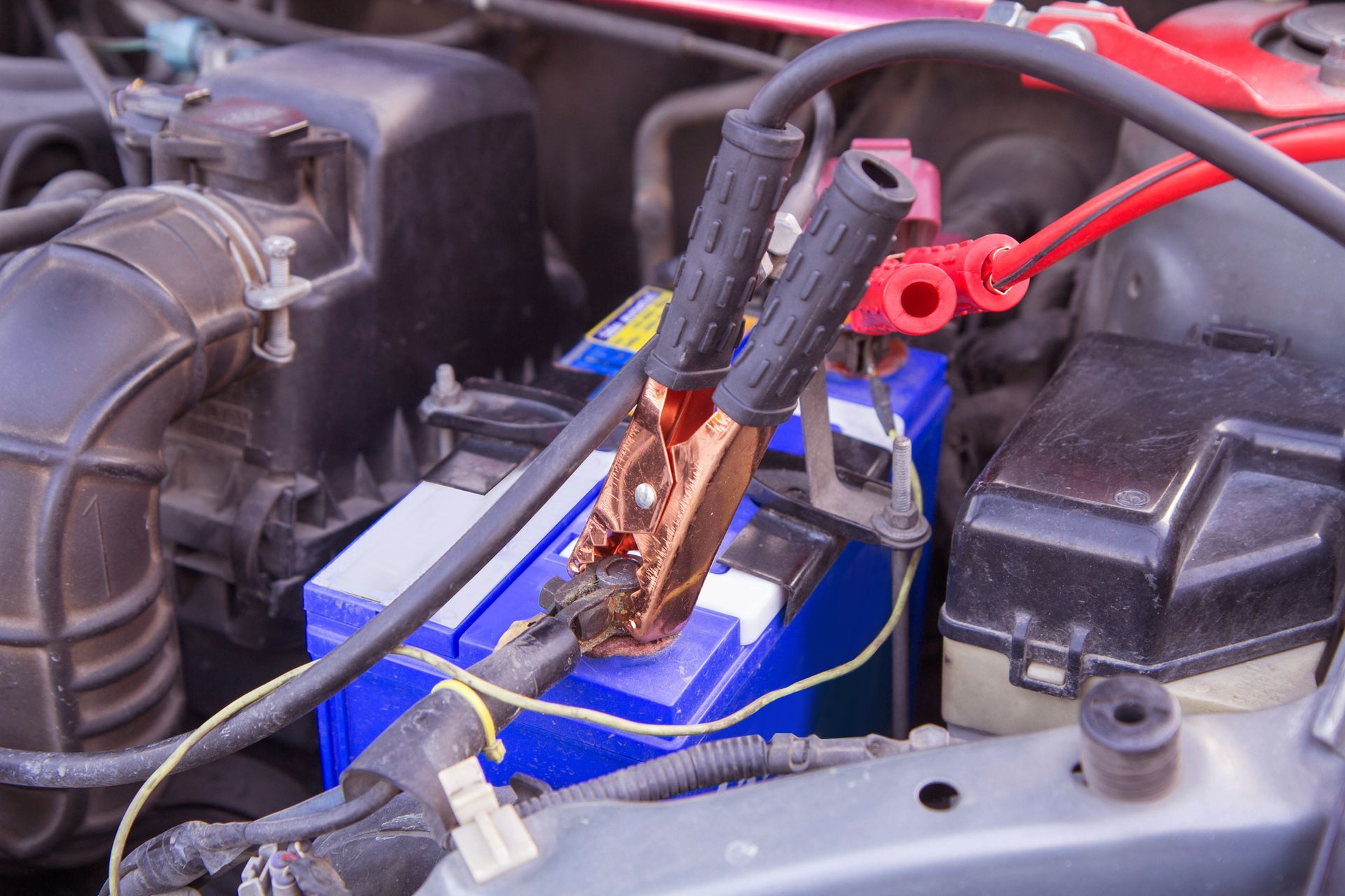 A car battery is being charged with jumper cables.