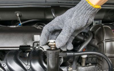 A person wearing gloves is working on a car engine.