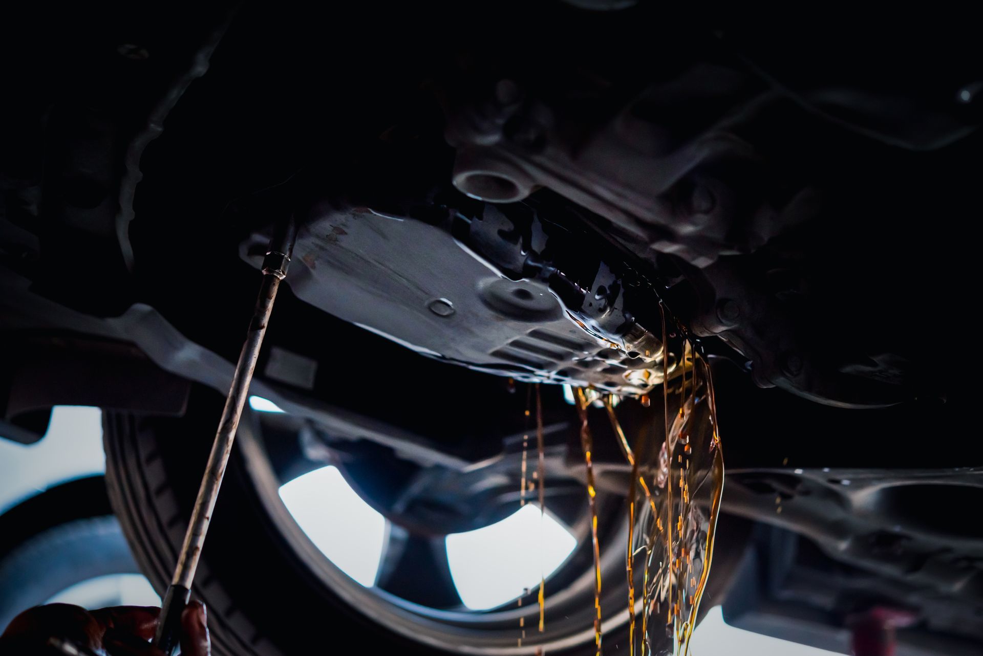 A person is working on the underside of a car.