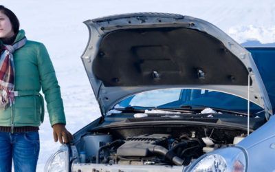 A woman is standing next to a broken down car with the hood open.