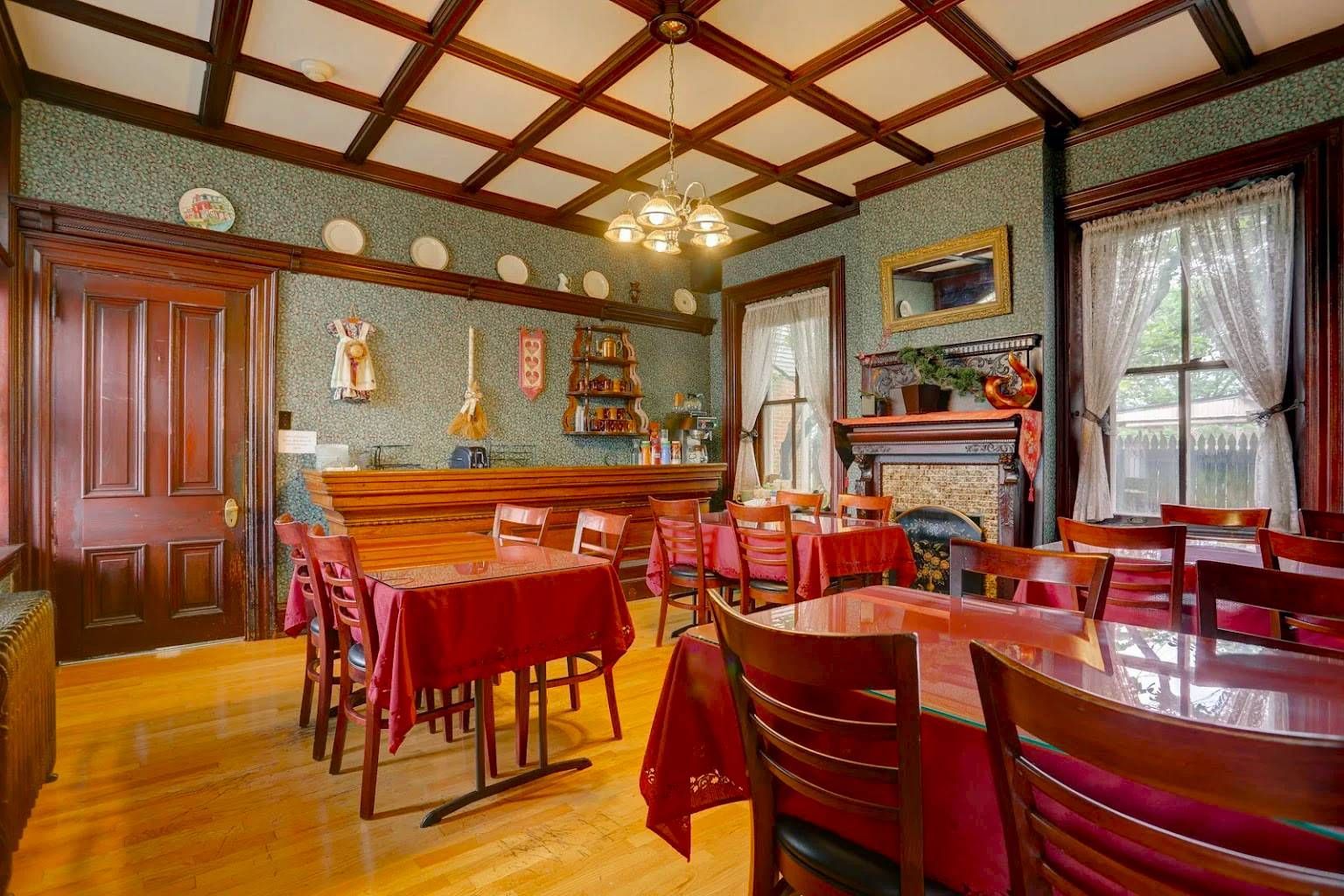 A dining room with tables and chairs and a fireplace.