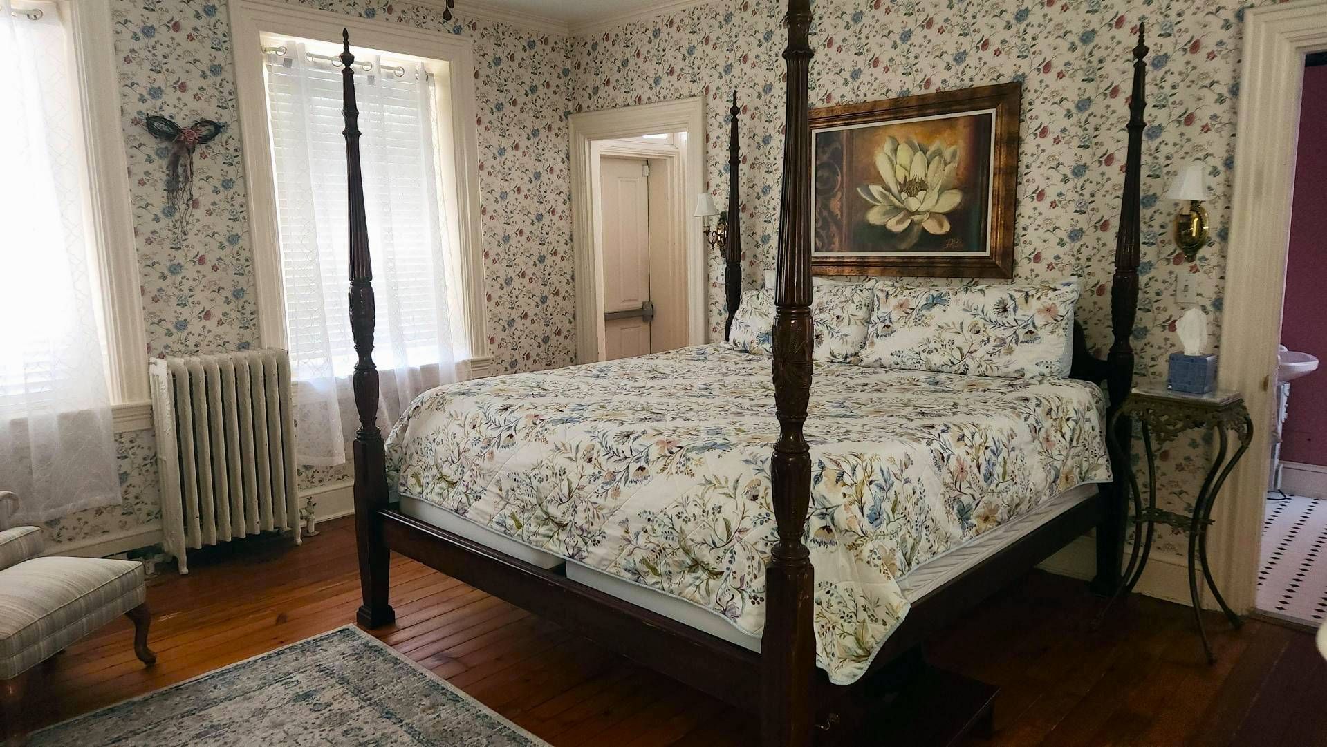 A bedroom with a four poster bed and a painting on the wall.
