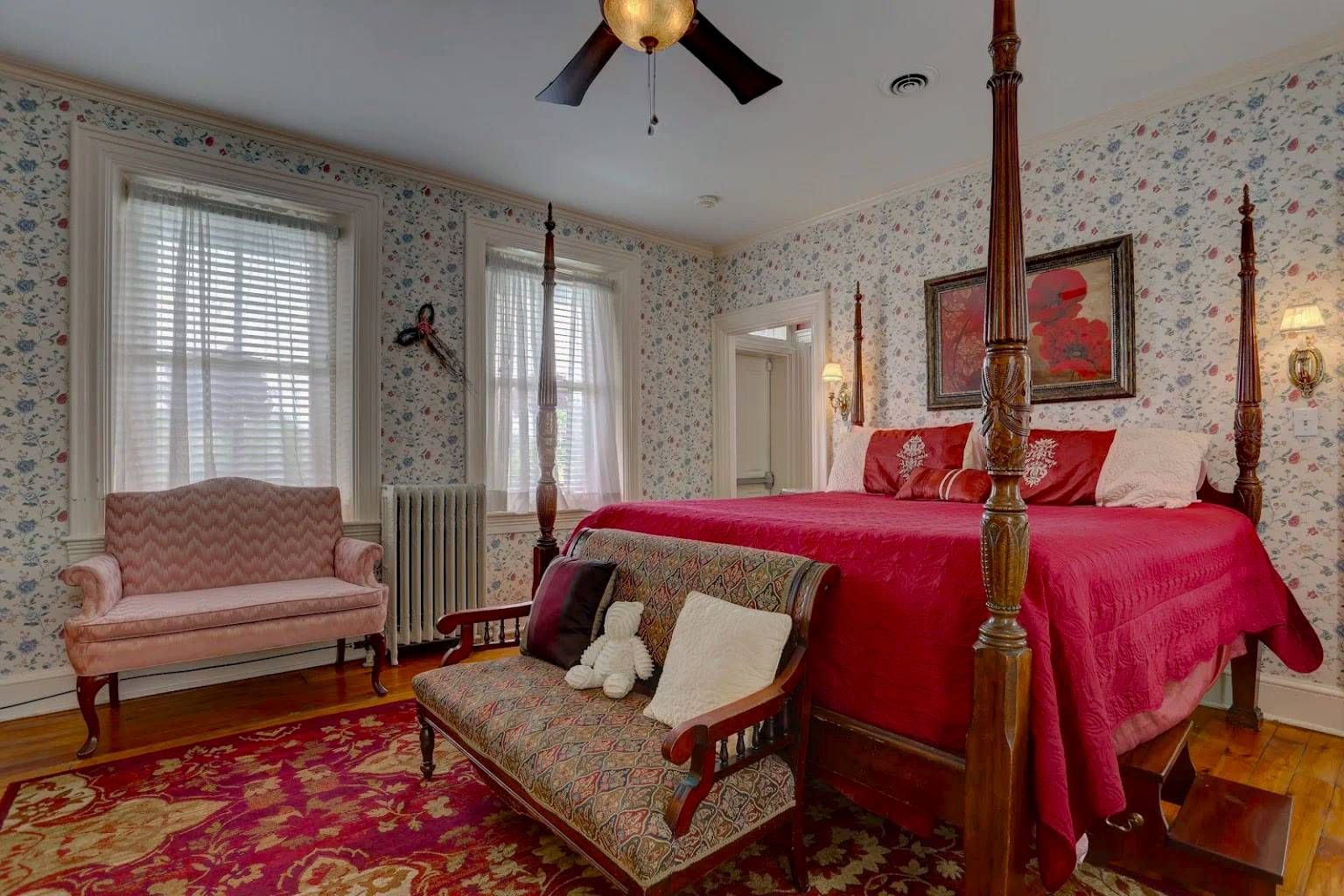 A bedroom with a four poster bed , a couch , and a ceiling fan.