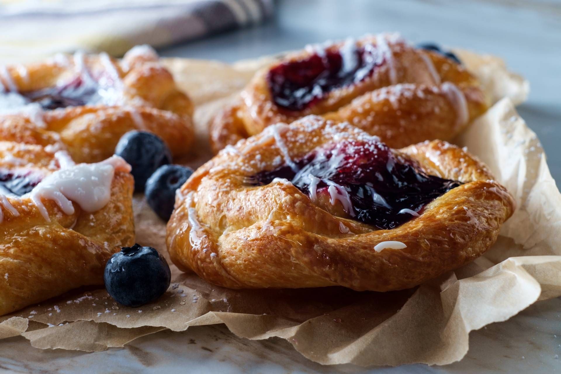 A close up of a bunch of pastries with blueberries on a table.