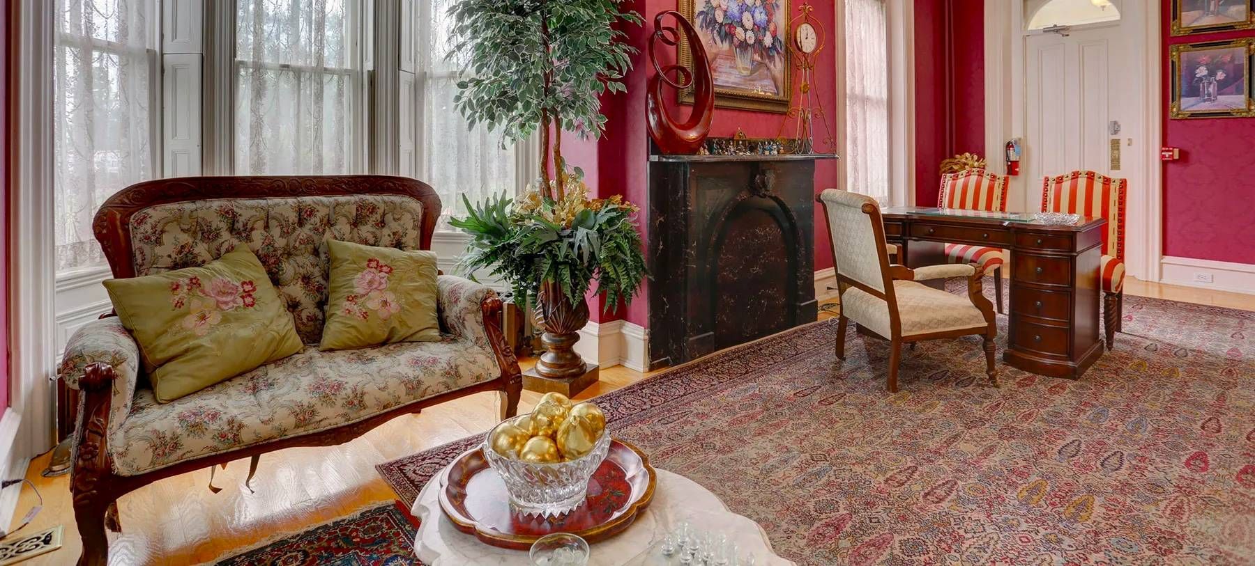 A living room with a couch , fireplace , chairs and a desk.