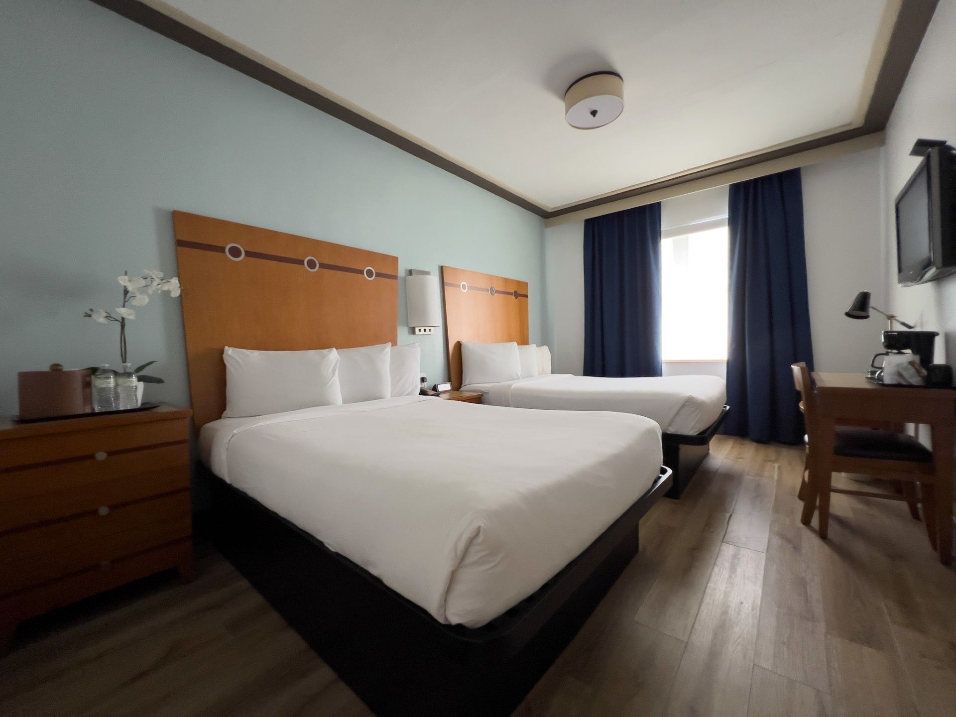 A hotel room with two beds , a desk and a television.