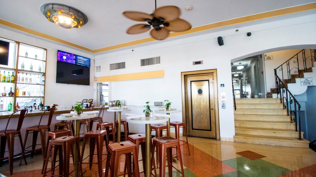 A restaurant with tables and stools and a ceiling fan