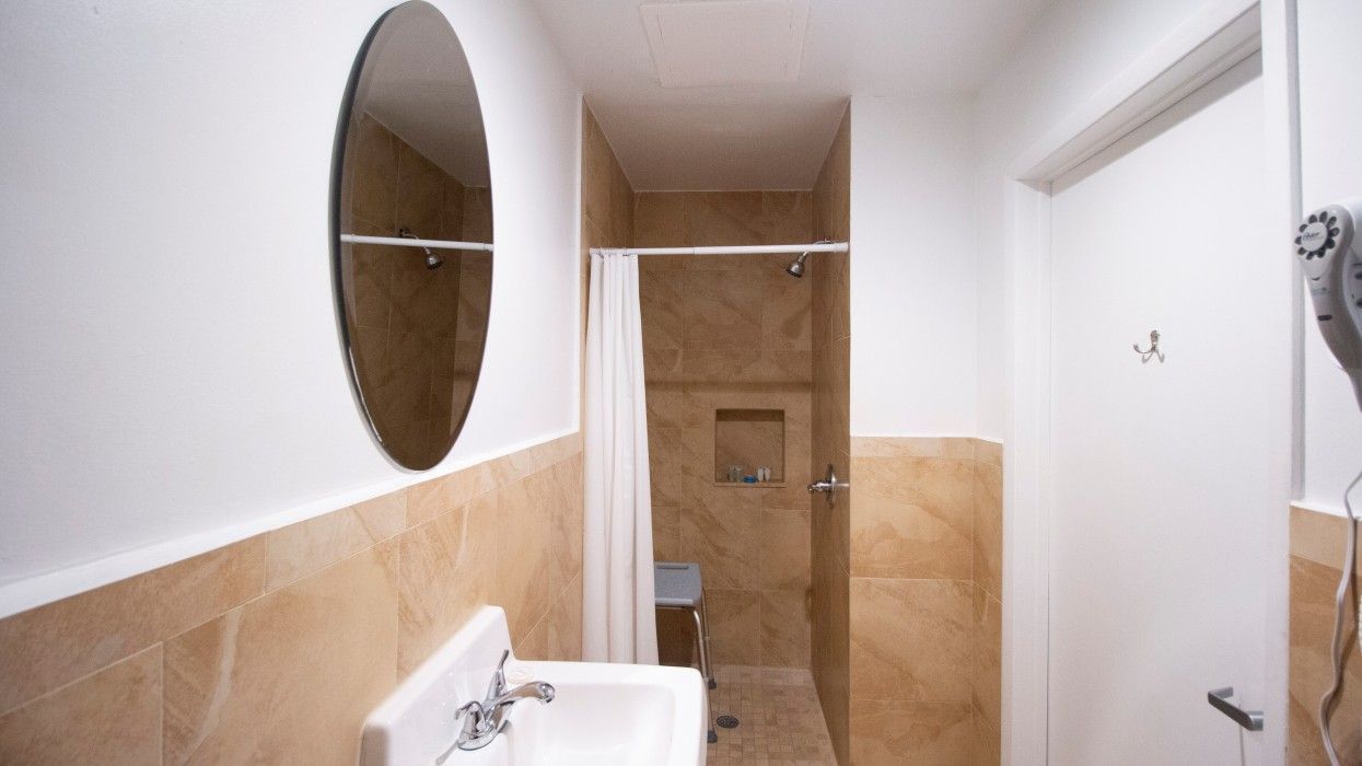 A bathroom with a sink , mirror and shower.