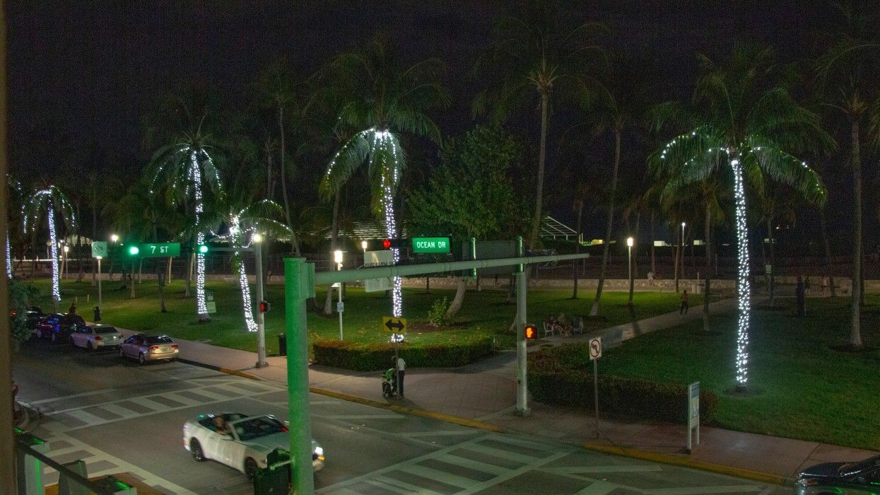 A white car is driving down a street at night.
