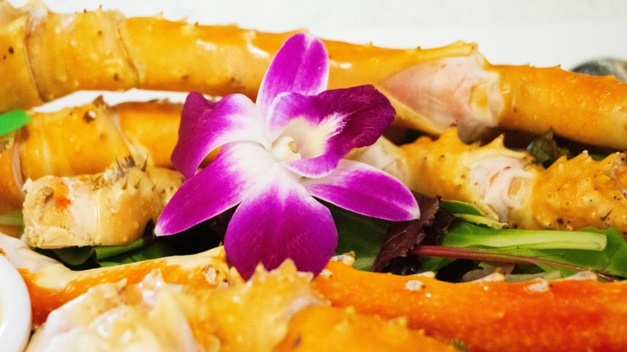 A close up of a plate of food with a purple flower on top.