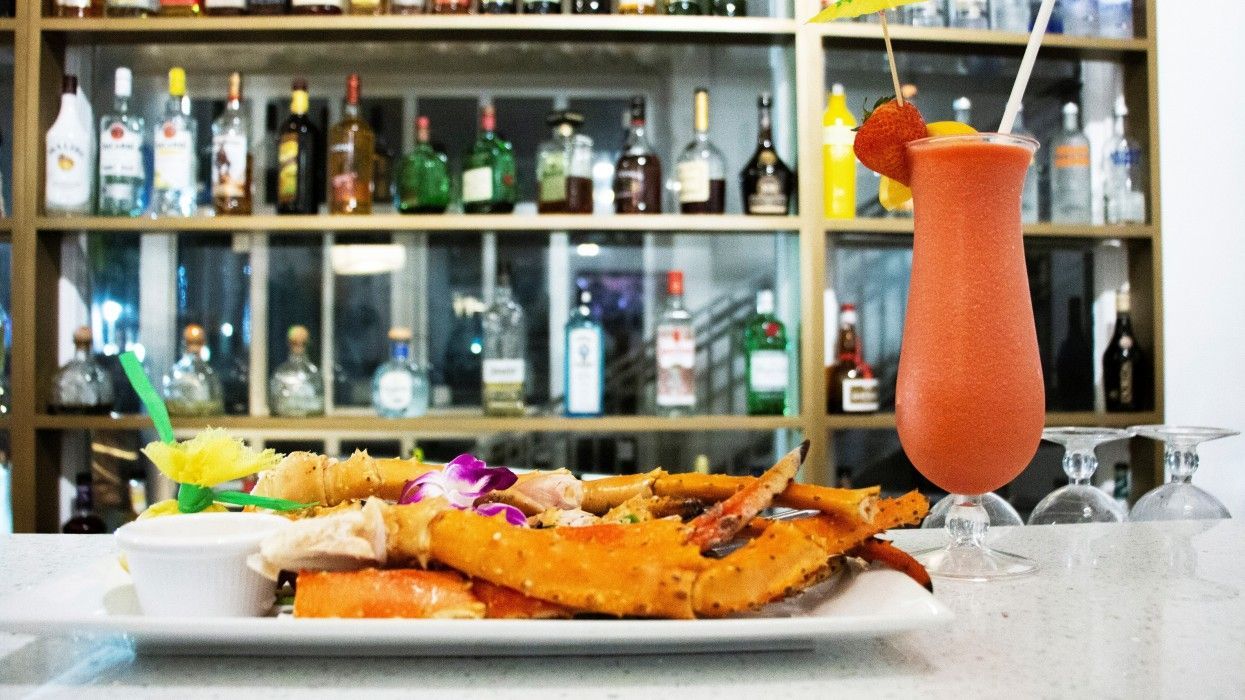 A plate of food and a drink are on a table in front of a bar.
