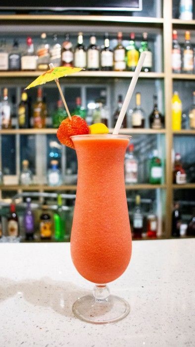A strawberry cocktail with an umbrella and straw in a tall glass