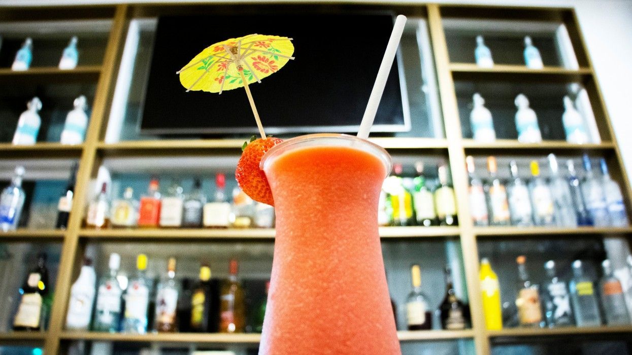 A drink with an umbrella on top of it in front of a bar.