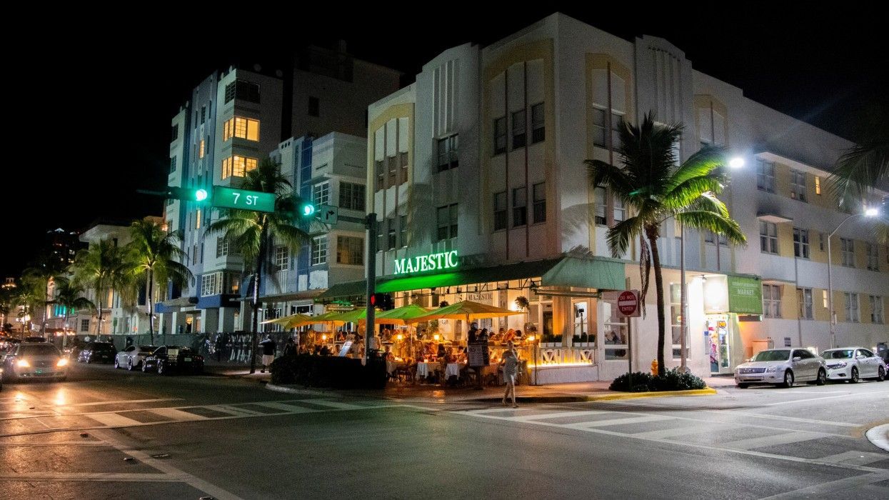 A city street at night with a restaurant in the middle of it
