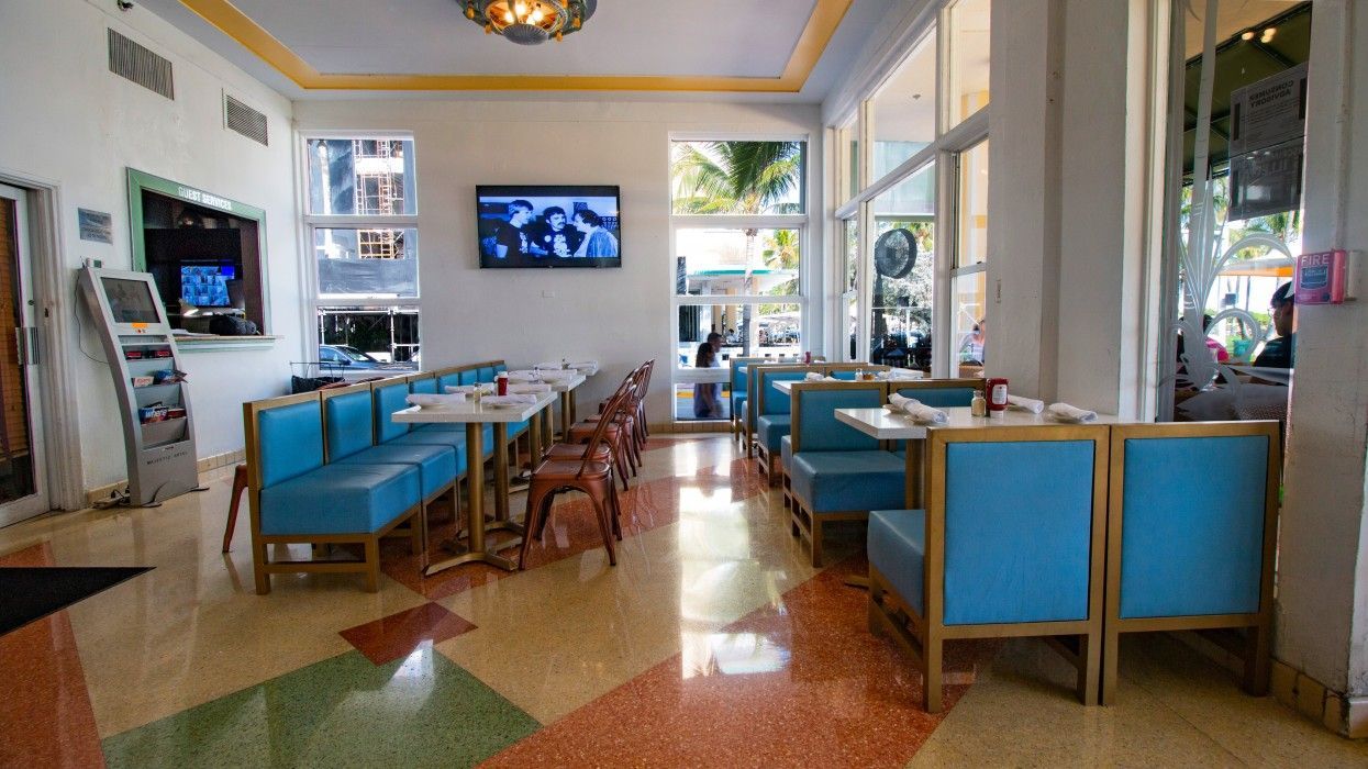 A restaurant with blue benches and tables and a television on the wall.