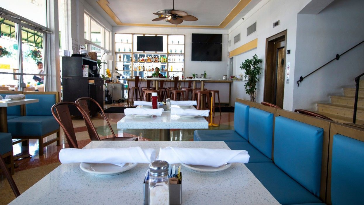 A restaurant with tables and chairs and a bar in the background