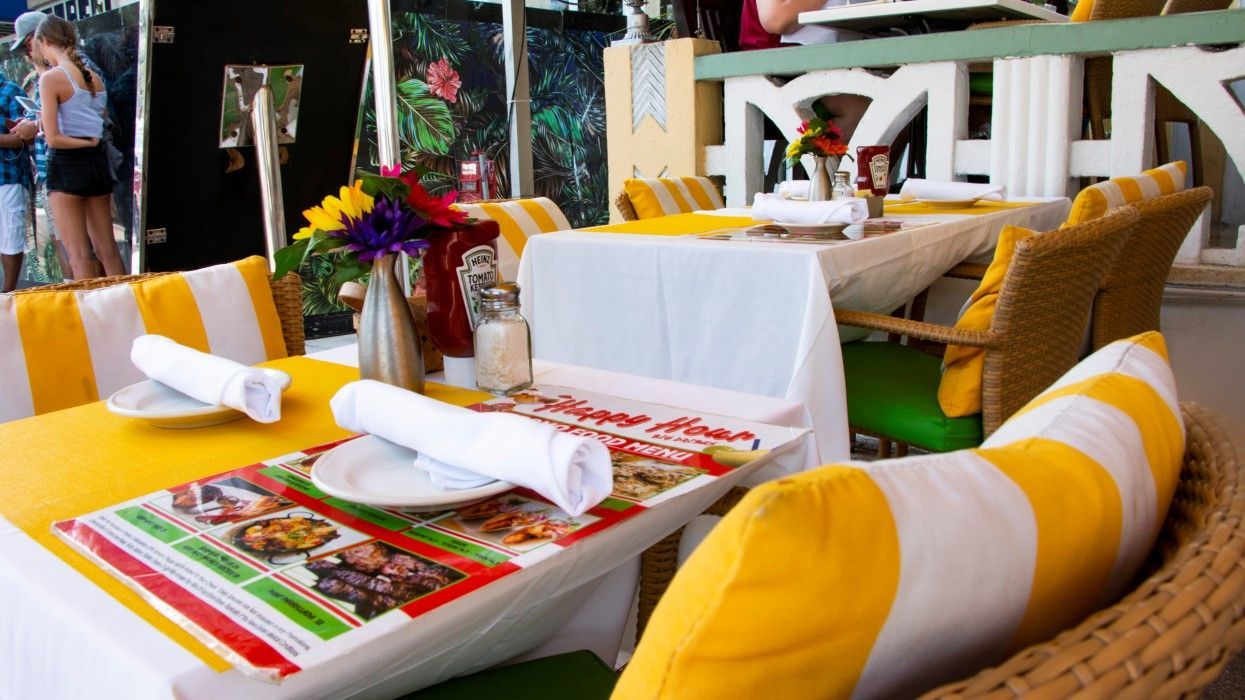 A restaurant with yellow and white striped chairs and tables.