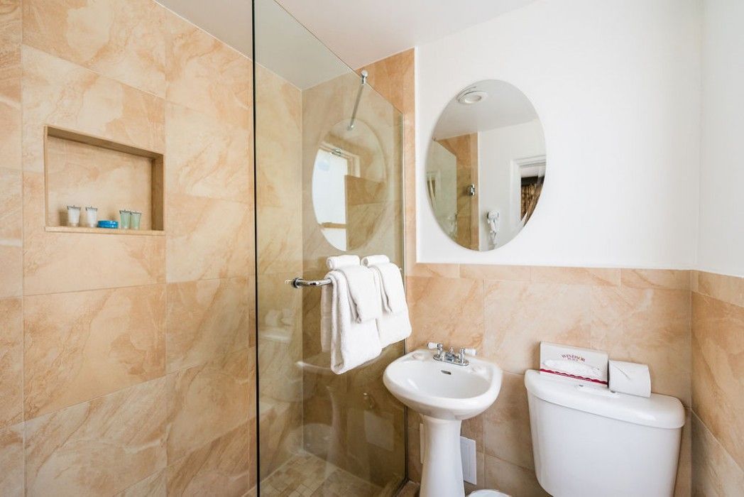 A bathroom with a sink , toilet , shower and mirror.