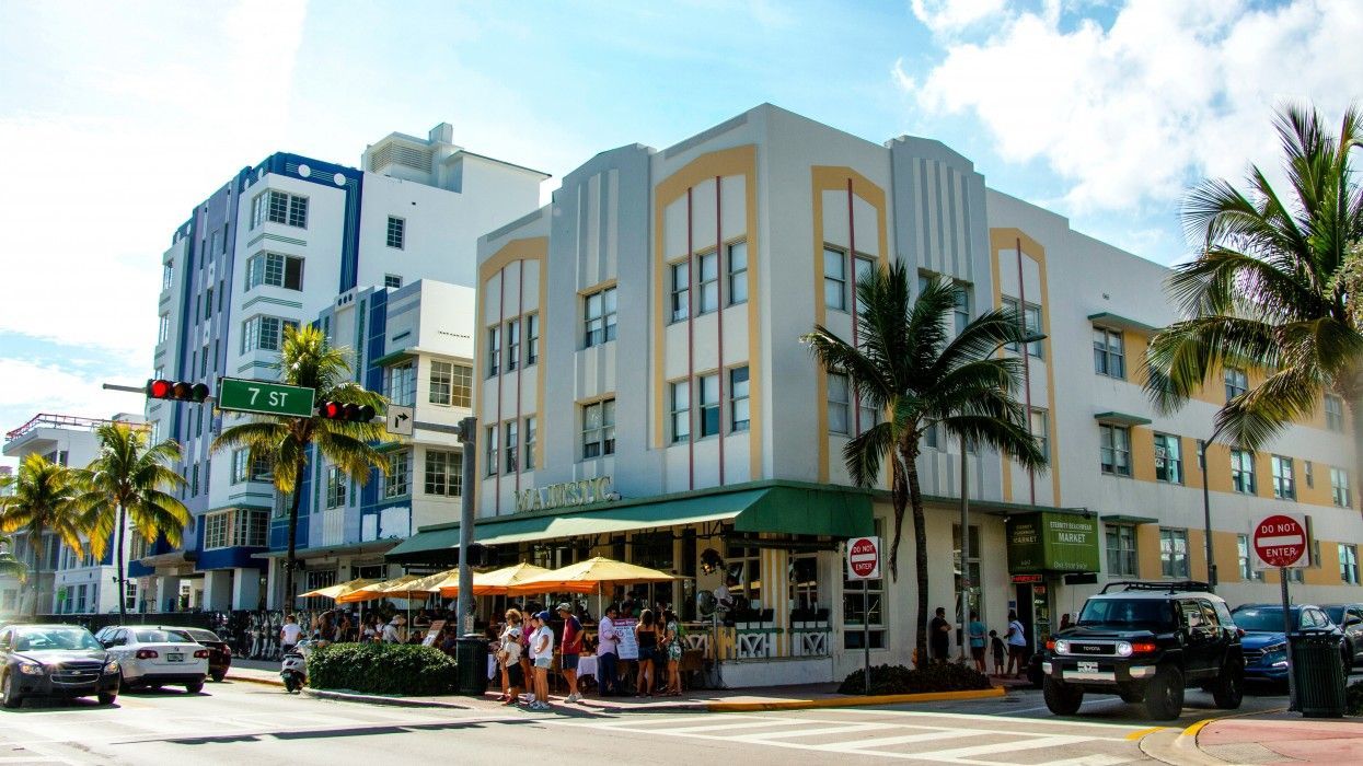 A group of people are standing outside of a building in a city.