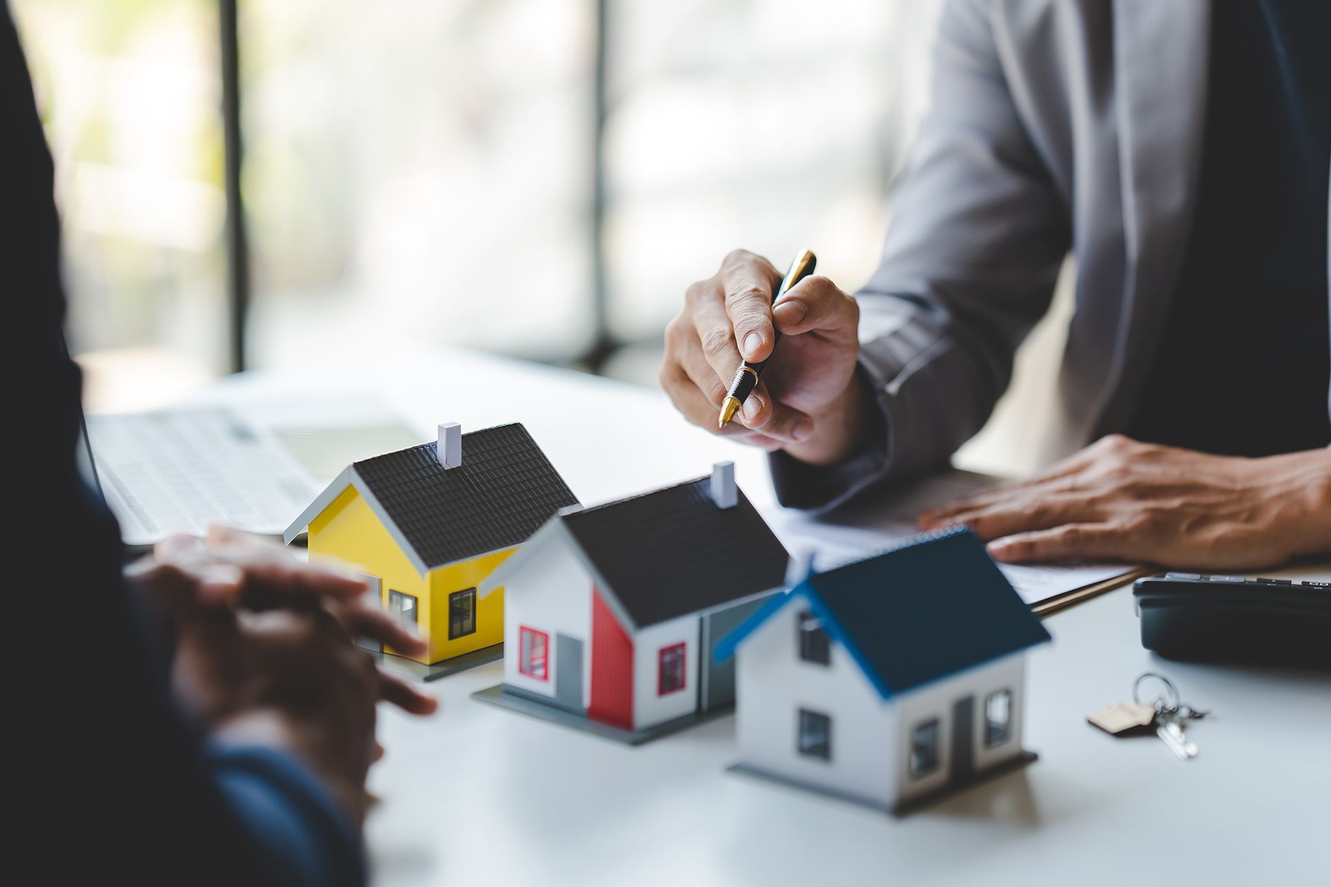 A group of people are sitting at a table with small houses and keys.